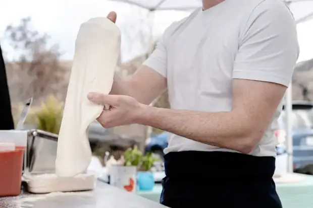 Chef hand-stretching Neapolitan pizza dough at the Biga trailer